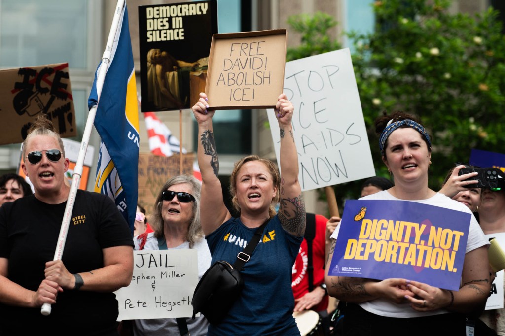 A group of protesters hold signs with messages such as “Free David! Abolish ICE!” and “Dignity, Not Deportation” during a demonstration.