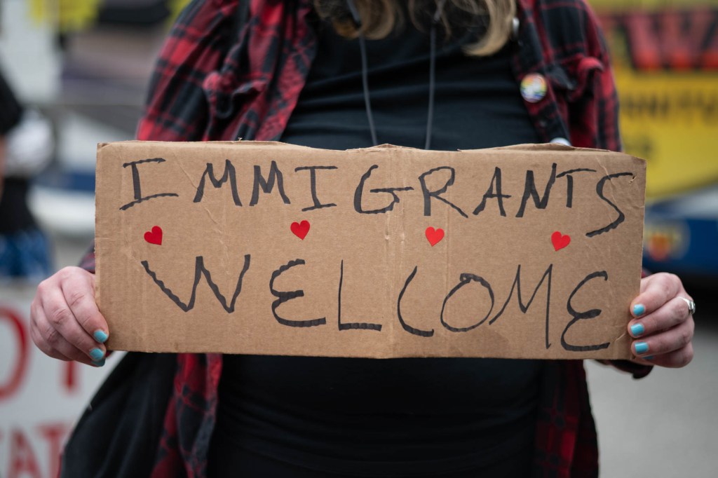 Person holding a cardboard sign that reads 